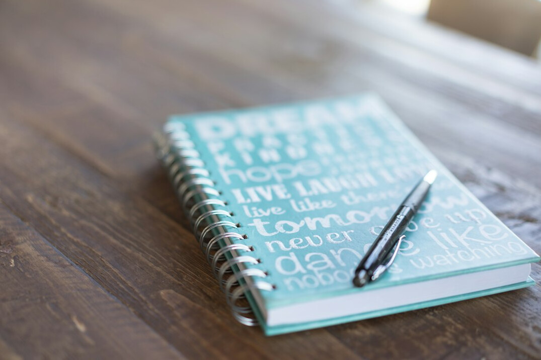 Hand writing in a notebook with a pen