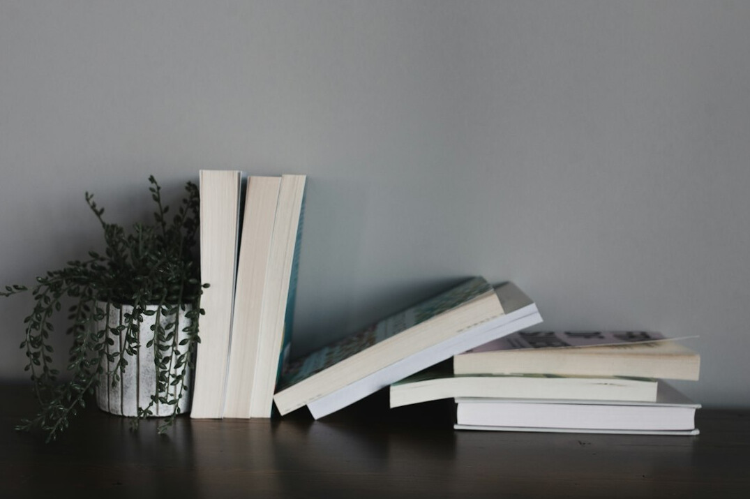 Stack of books and notebook on a wooden desk